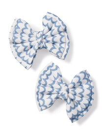 The Girls Hair Bows in La Mer by Petite Plume, featuring charming white and light blue scalloped patterns, make the perfect accessory for girls. Positioned diagonally on a plain white background, these elegant bows add a touch of sophistication to any outfit.