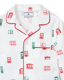 The Petite Plume Kids Maisonette x Petite Plume Night Before Pajama Set features white pajamas with red piping and a festive green and red window print, complete with a chest pocket. Perfect for those who enjoy luxurious sleepwear.