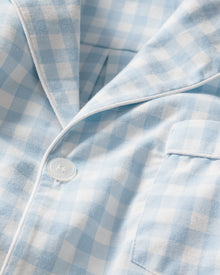 A close-up of the Mens Twill Pajama Short Set in Light Blue Gingham by Petite Plume shows its cotton fabric resembling mens sleepwear with a buttoned-up section, visible button, pocket, soft texture, detailed stitching, and luxurious feel.