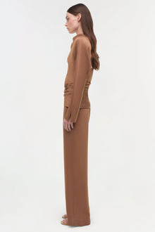 Woman wearing camel-colored satin wide-leg pants with long sleeves, shown in profile view.