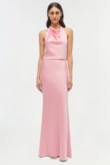 Woman wearing a pink sleeveless halter gown with draped neckline and fitted silhouette.