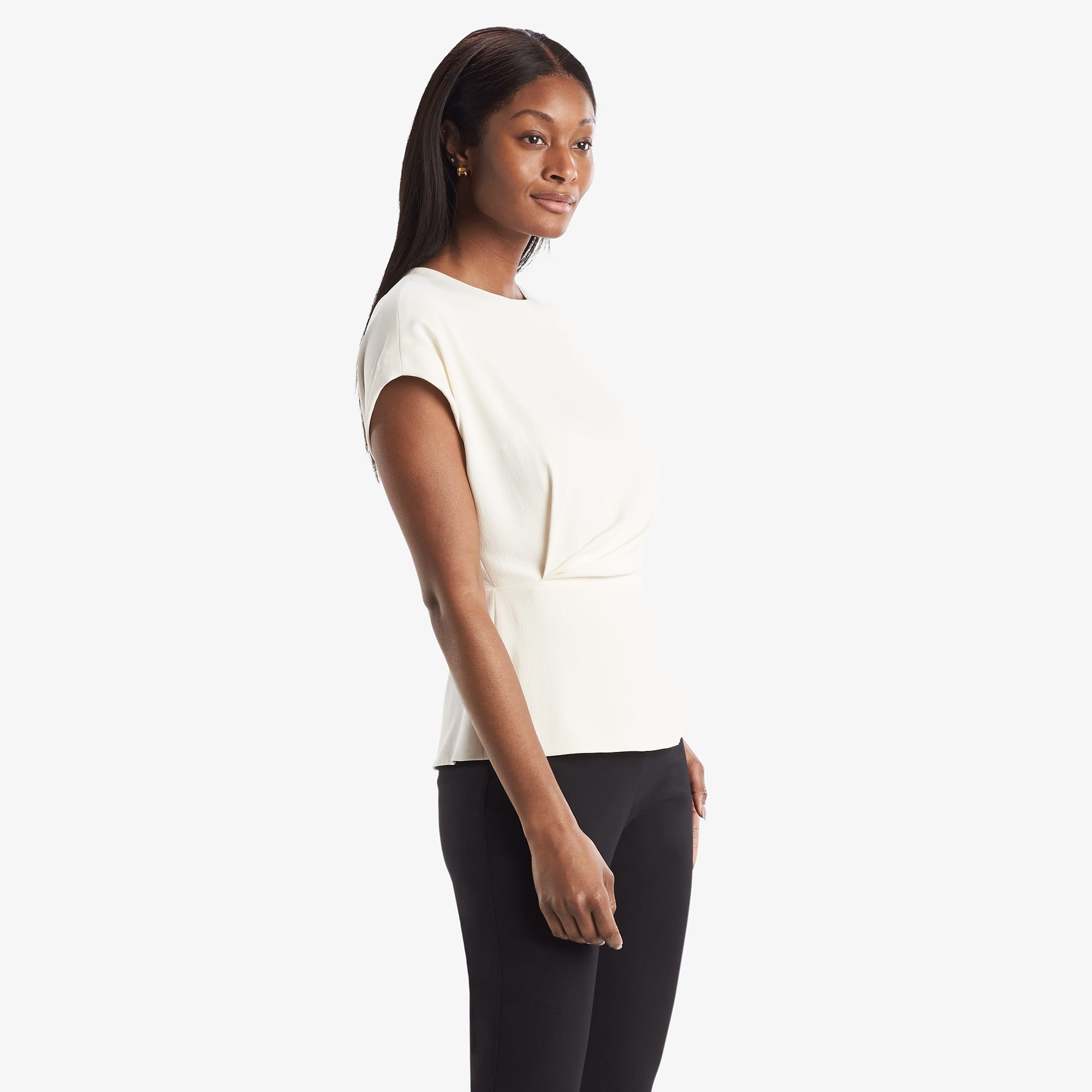 Side image of a woman standing wearing the Nejvi Top in alabaster | Exclude