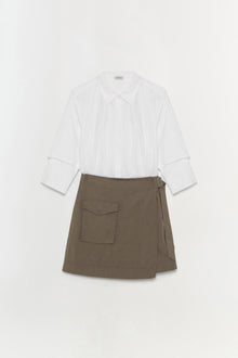 White collared shirt with rolled cuffs paired with olive-brown wrap skirt featuring a patch pocket.
