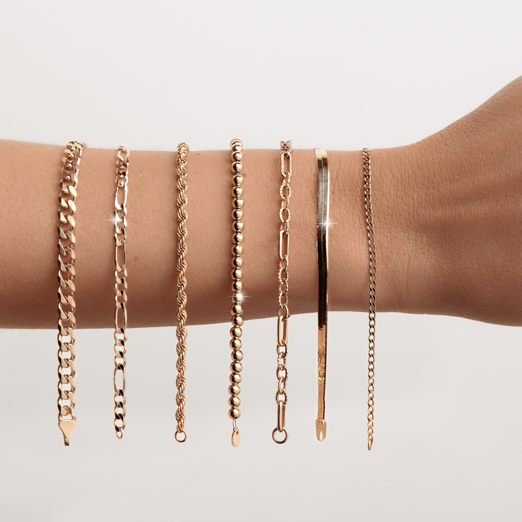 Lifestyle Model. Close up of woman's arm with 7 gold chain bracelets hanging on it
