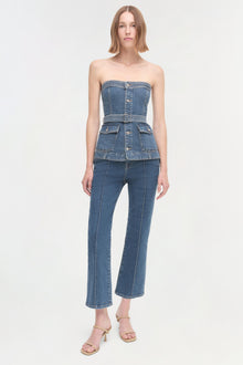 Woman wearing a strapless denim corset top with a waistband and cropped flared jeans.