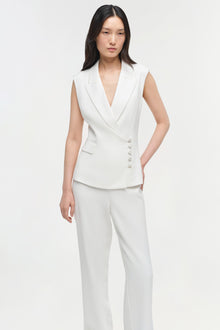 White straight leg trousers with high waist, worn with matching sleeveless blazer vest.