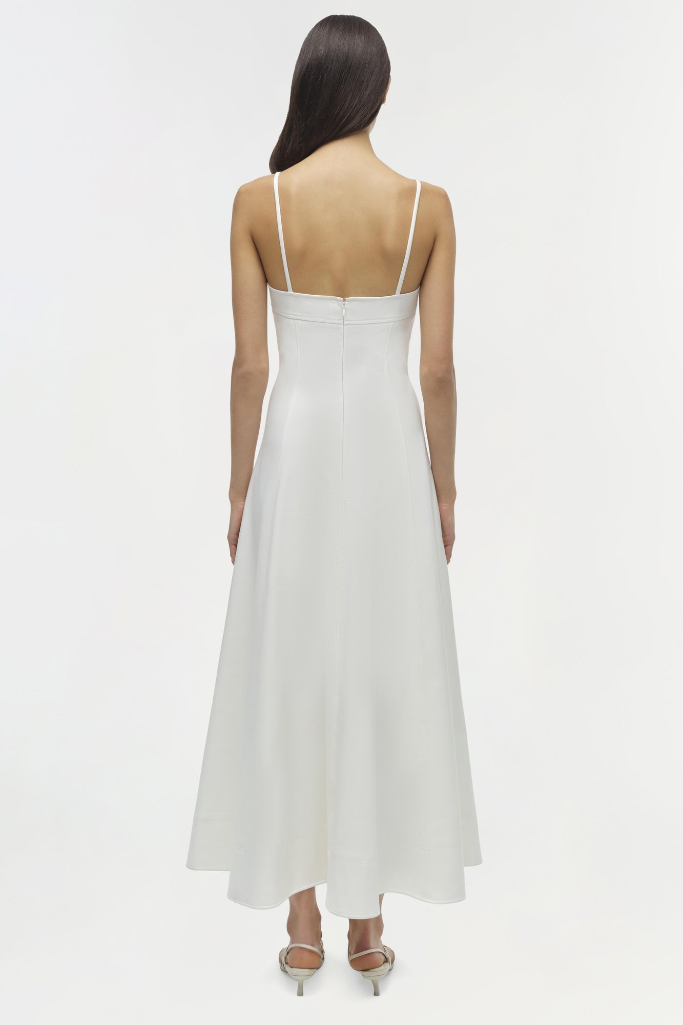 White sleeveless midi dress with thin straps and open back, shown from behind on model.