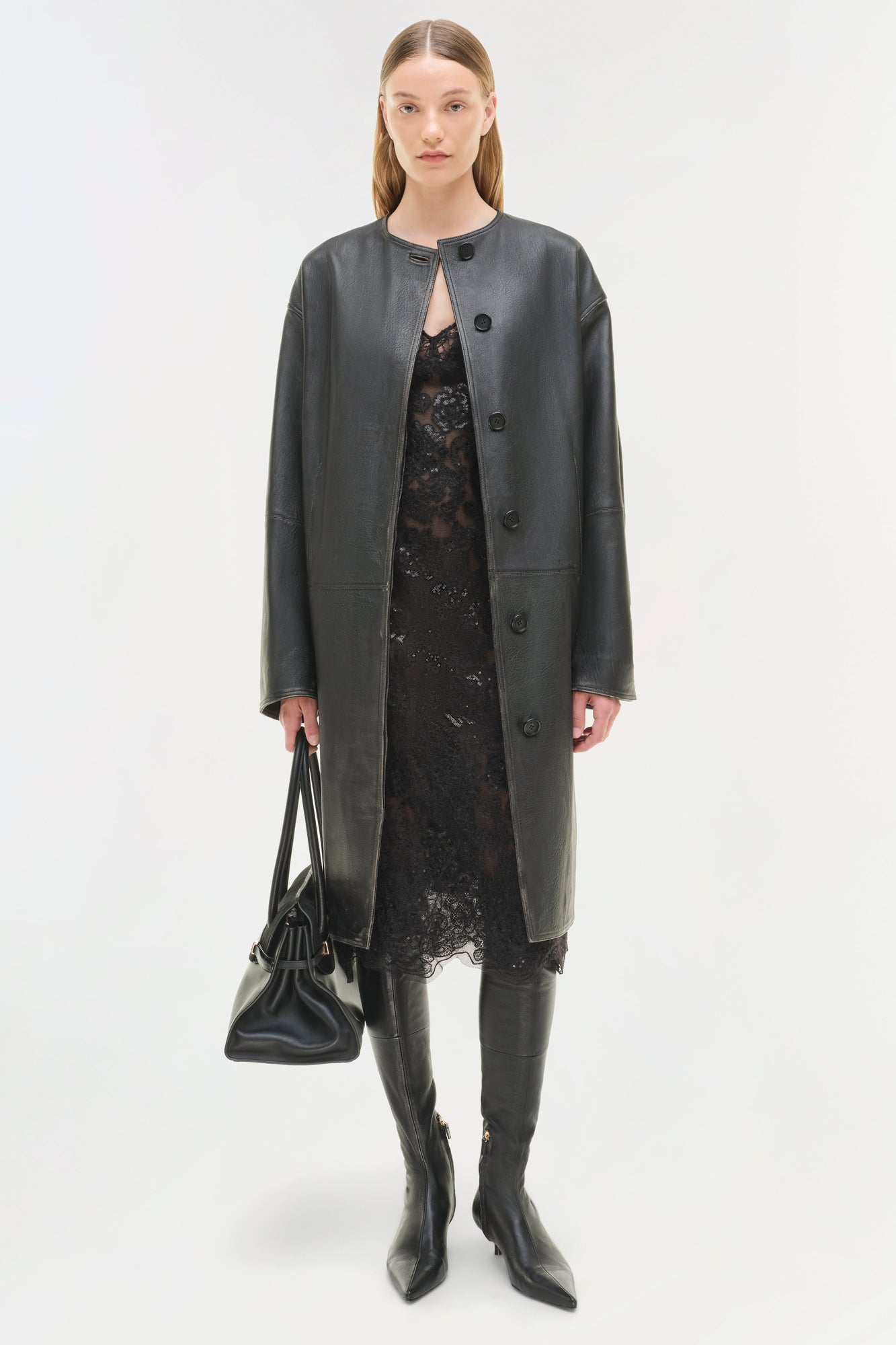 Dark gray leather coat worn open over black lace dress, paired with black leather boots and handbag.