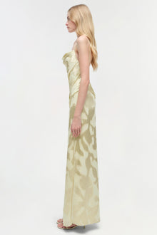 Pale yellow sleeveless floor-length gown with abstract leaf pattern shown on model from side profile.