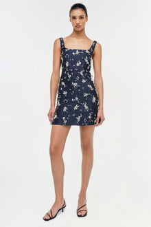 Navy mini dress with white floral jacquard pattern, square neckline, and sleeveless design.