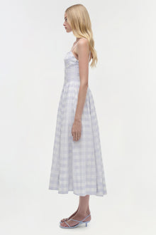 Woman wearing light blue and white gingham midi dress with thin straps, shown from the side.