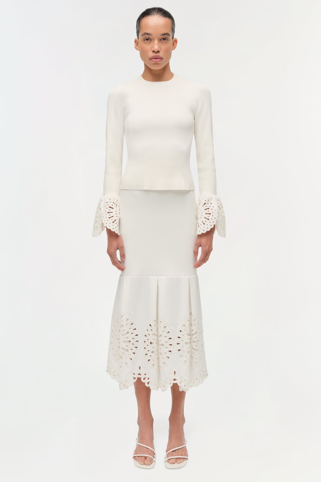 Cream knit top with long sleeves featuring lace cuffs and matching midi skirt with lace hem detail.