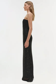 Woman wearing a black sequin strapless gown with floor-length silhouette, shown in profile view.