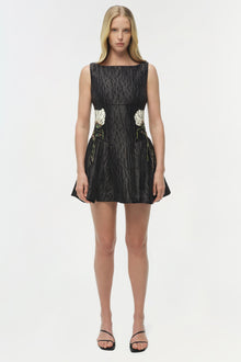 Black sleeveless mini dress with textured fabric and white floral embroidery on the sides.