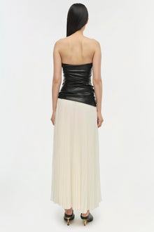 Strapless dress with ruched black leather bodice and ivory pleated skirt, back view.