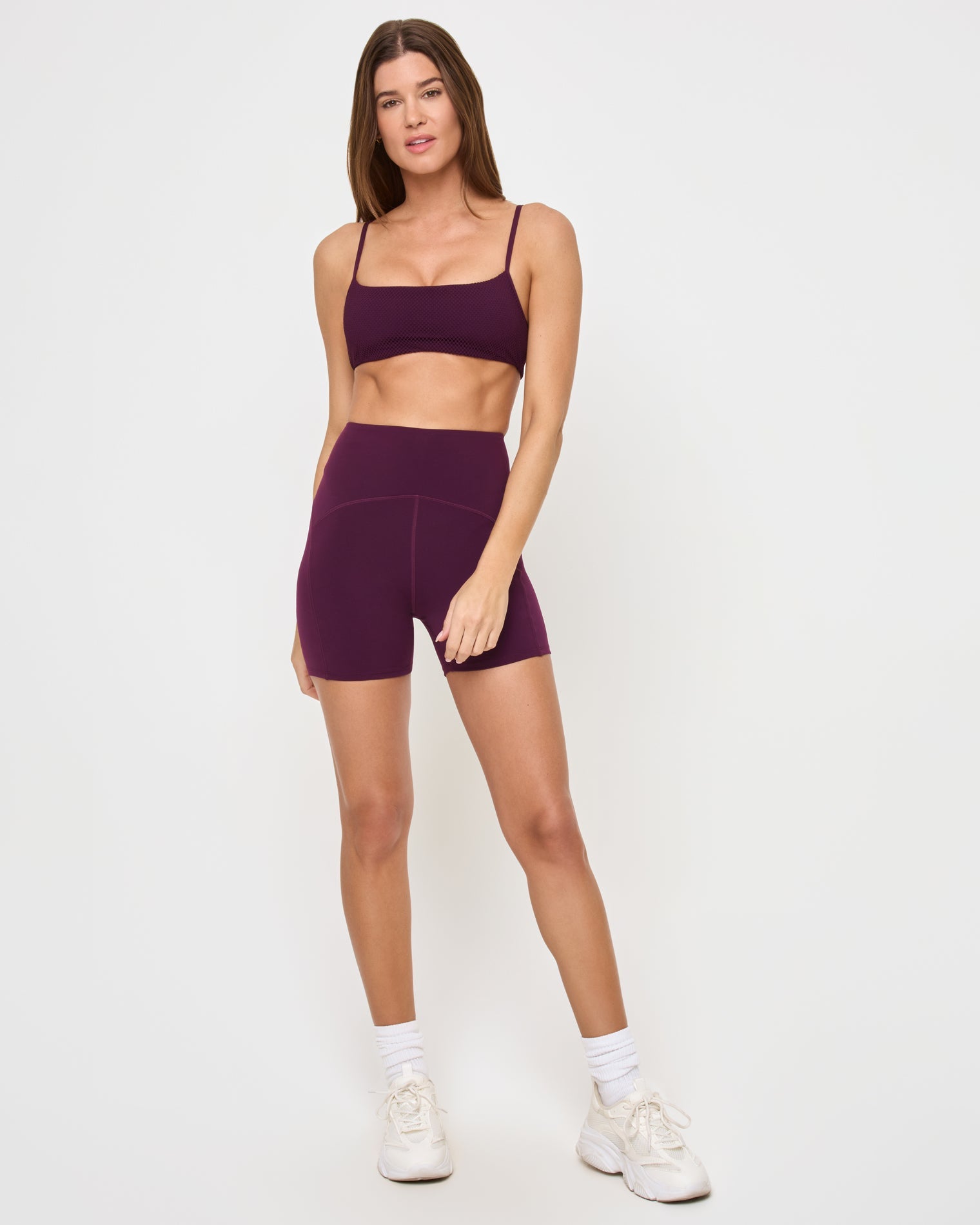 Front view of the LSPACE En Pointe Short in plum on a model against a white background, showing the high-waist active shorts, paired with the matching plum Stride Bra.