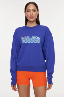 Model wears a royal blue crewneck sweatshirt with the lettering 