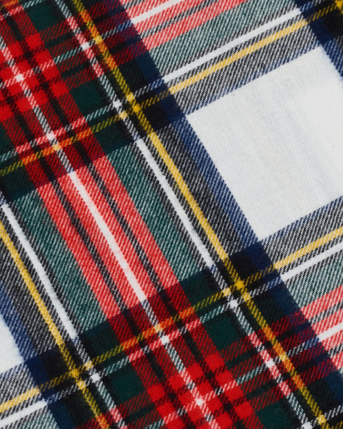 Close-up of Petite Plumes Flannel Sheets in Balmoral Tartan, featuring a vibrant crisscross pattern with intersecting lines in red, green, yellow, navy, and white.