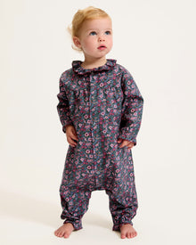 Baby's Twill Madeline Romper in Fleurs de Saison features long sleeves, a dark base with pink and purple floral print, front snap closures, a rounded collar, and gathered cuffs at wrists and ankles.