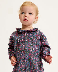 Baby's Twill Madeline Romper in Fleurs de Saison features long sleeves, a dark base with pink and purple floral print, front snap closures, a rounded collar, and gathered cuffs at wrists and ankles.