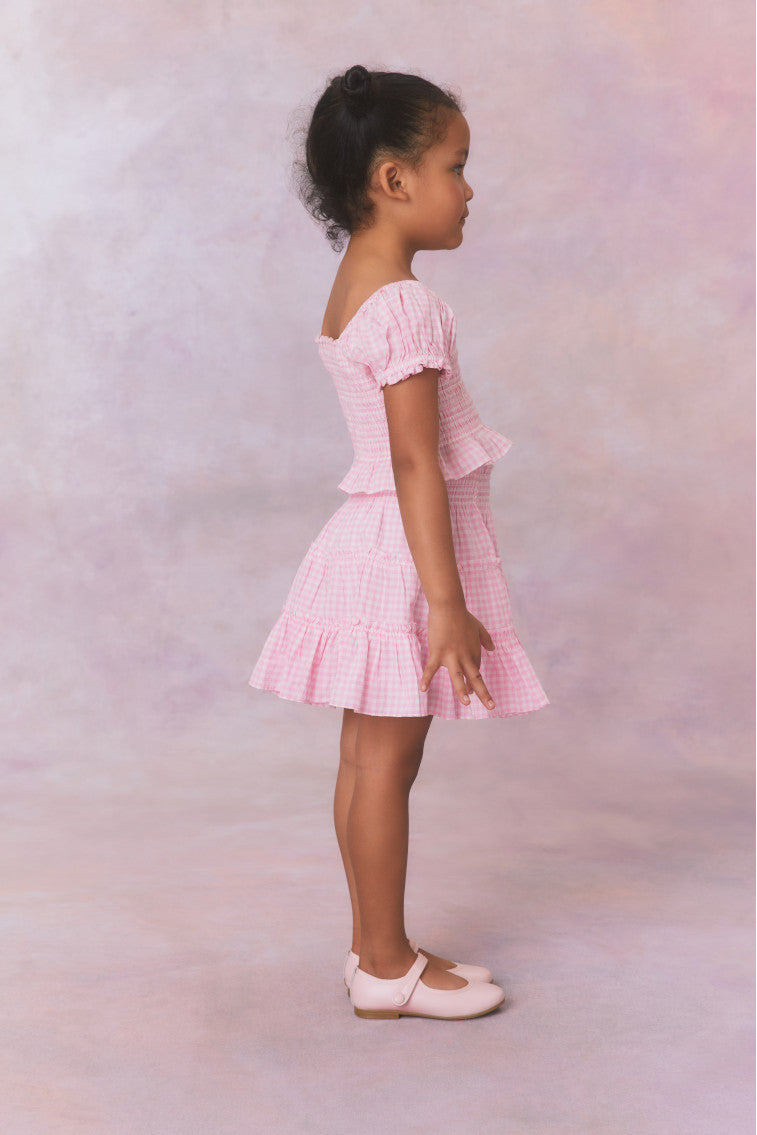 Pink gingham cotton off the shoulder top with puff sleeves and a smocked bodice flowing to a peplum finish for girls.