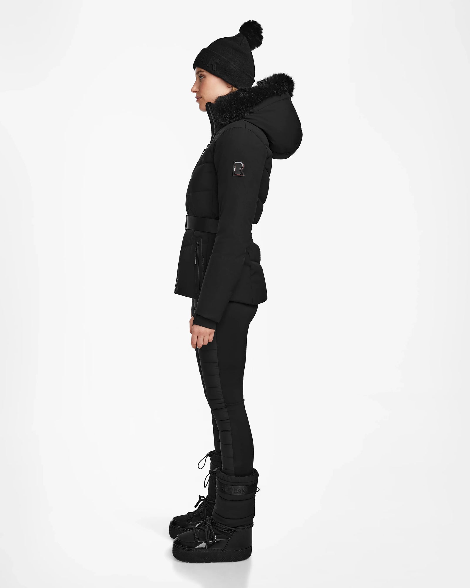 A woman in the Rudsak ALAIA - 8124816 Black quilted ski jacket stands confidently, ready for the slopes with advanced ski-specific features and optional RECCO rescue technology.