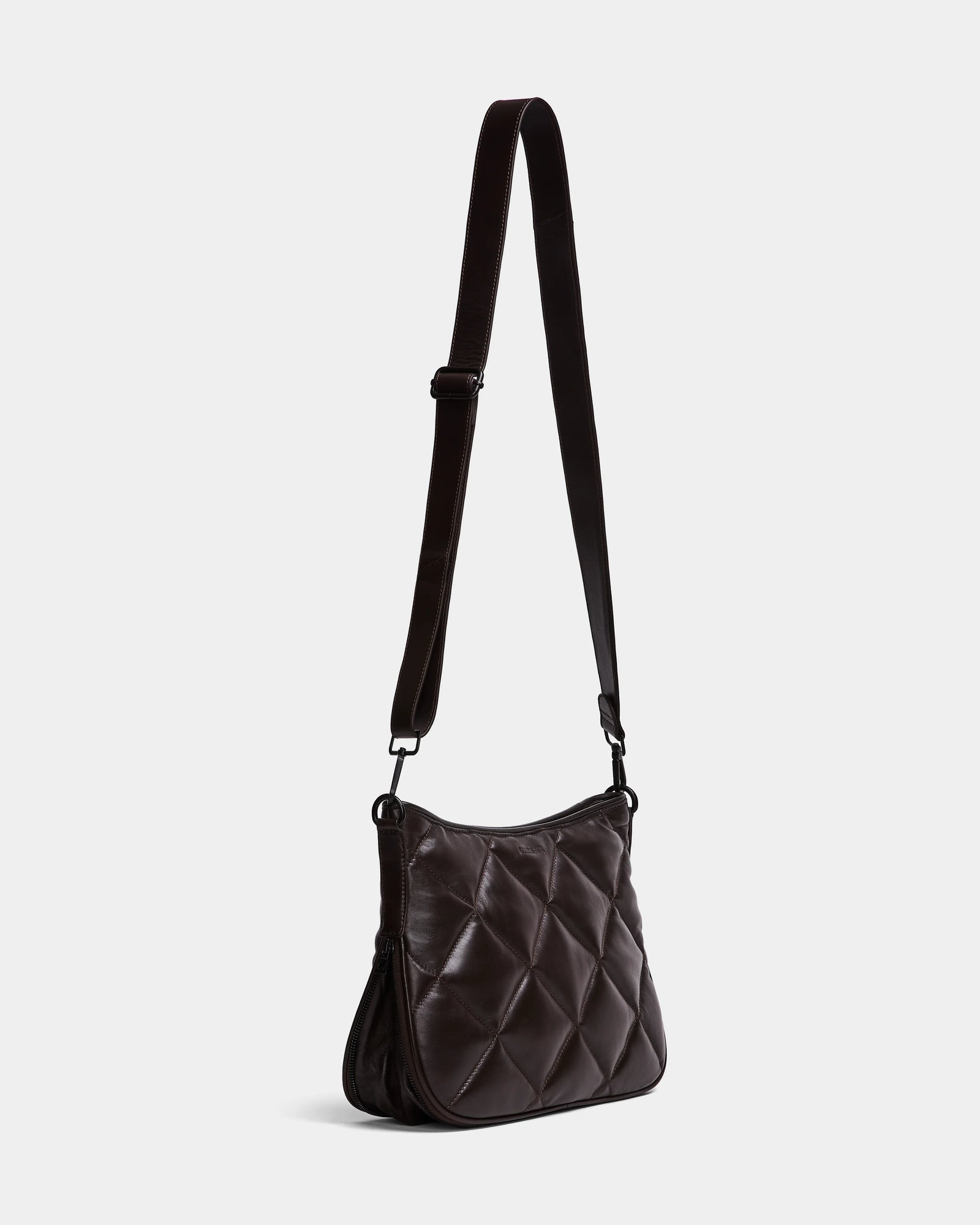 The Rudsak ALICIA - 8323507 Espresso is a womens dark brown quilted purse with an adjustable strap, soft padded texture, and a rectangular shape with gently rounded edges, shown against a plain light gray background.