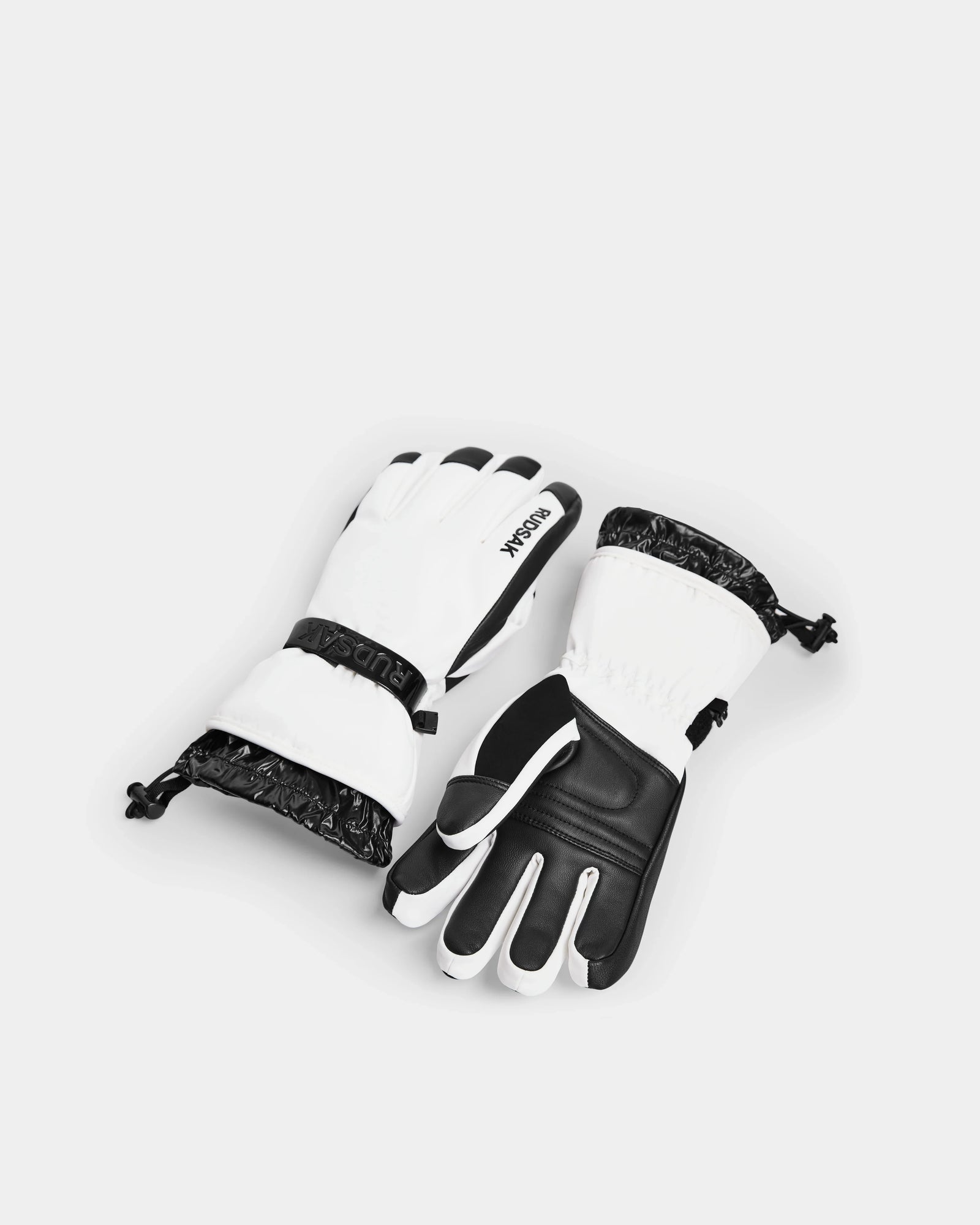 The Rudsak APLEN - 6424505 Optic White ski gloves feature black and white insulation, waterproof zippers, and adjustable wrist straps. Shown on a white background with one glove palm up and the other palm down.