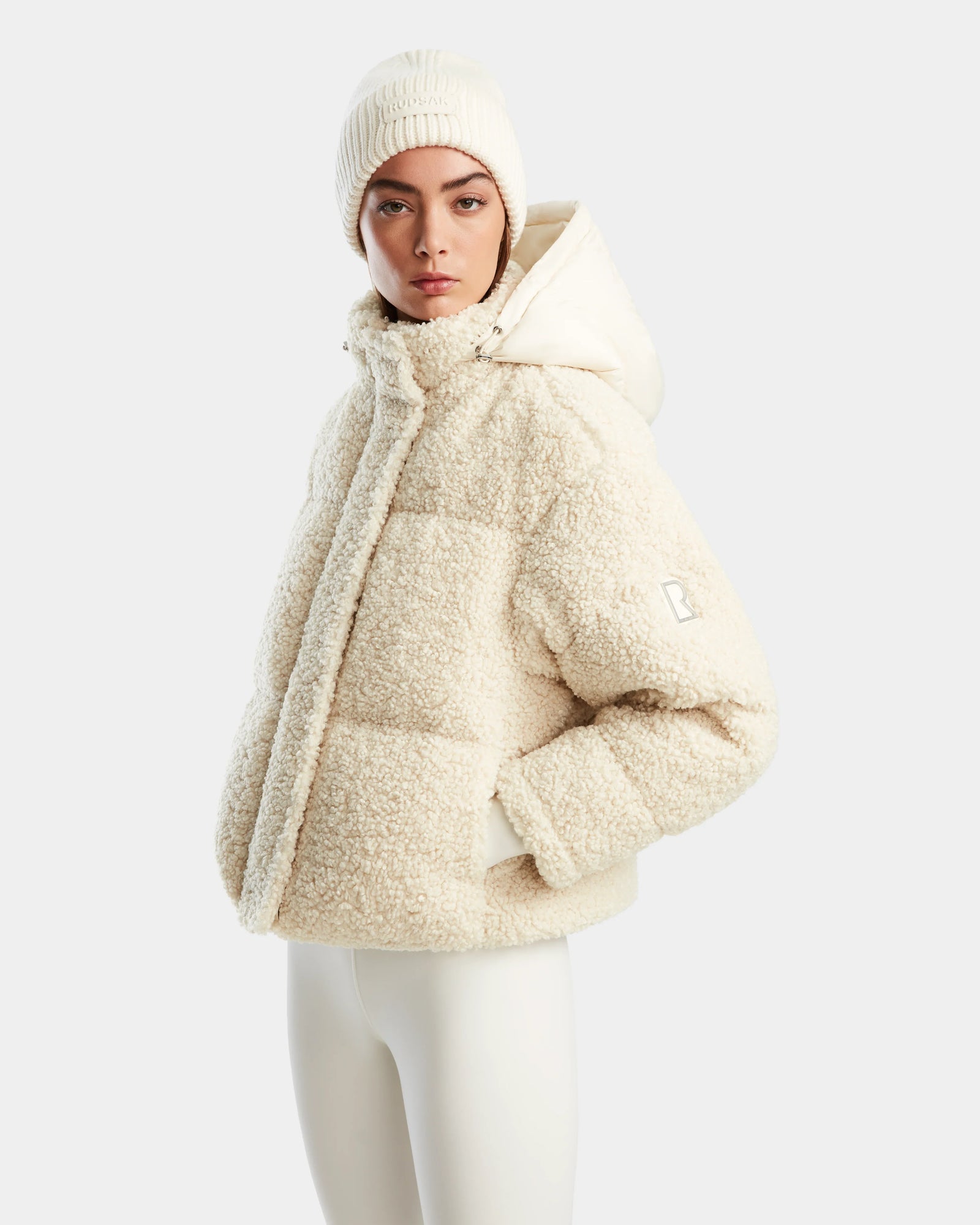 A woman wears the Rudsak IKSA - 8124706 Iceland white winter puffer coat and a matching hat.