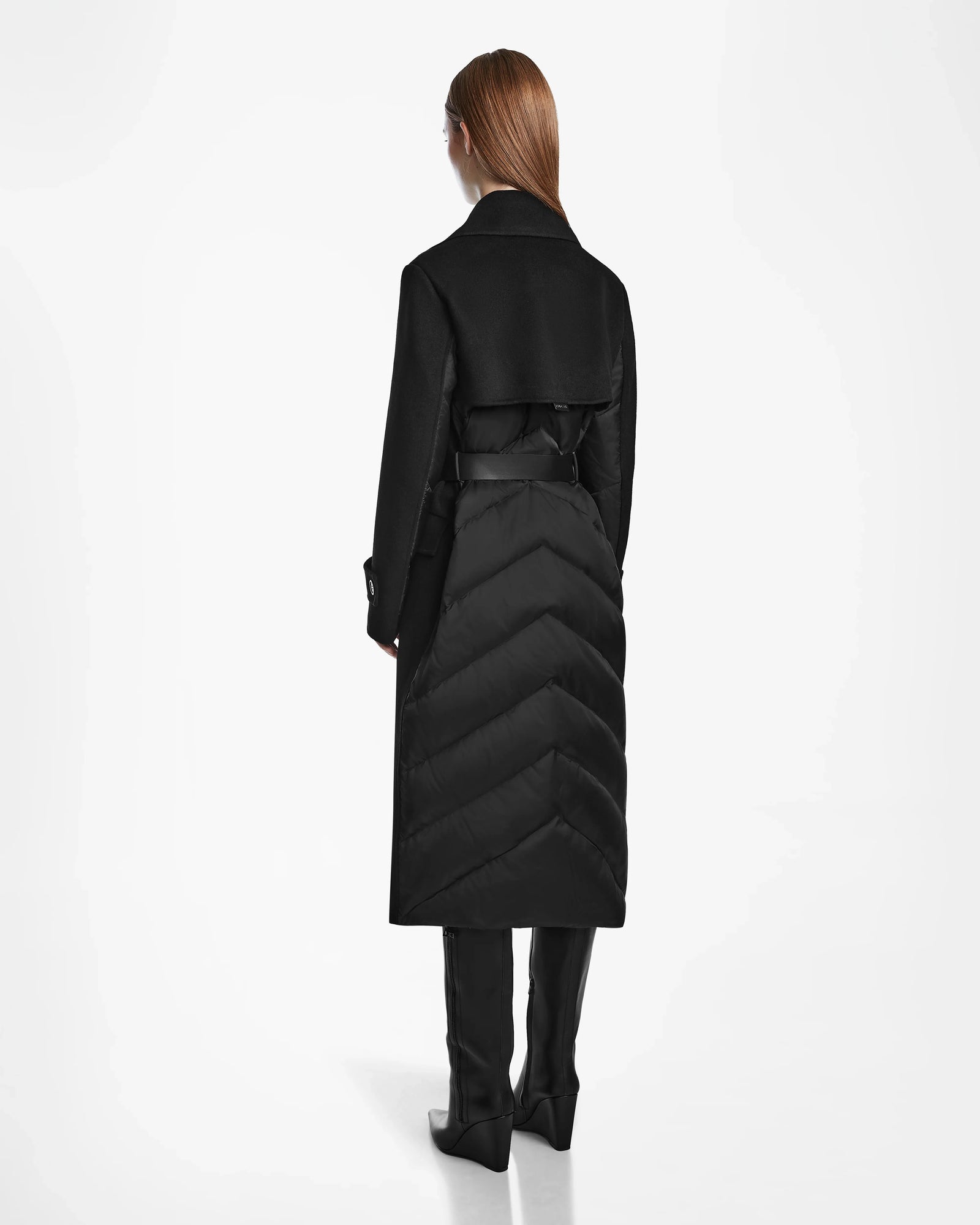 A person with long, straight hair is seen from behind, wearing the Rudsak IVE - L124560 Black womens wool blend coat, paired with black pants and knee-high boots against a plain white background.