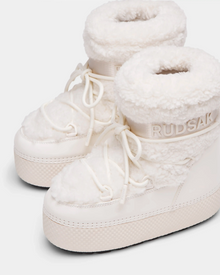 The KATHY Y - 1224500 Iceland by Rudsak are white winter boots featuring thick soles, plush faux fur trim and lining, lace-up fronts, water-repellent finish, and Rudsak branding embossed on the side.