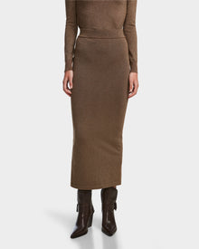 A person wears the MONICA - 8524516 Antique Bronze fitted women’s knit skirt by Rudsak, styled with a matching brown top and dark brown heeled boots, against a white background. Upper body partially visible.