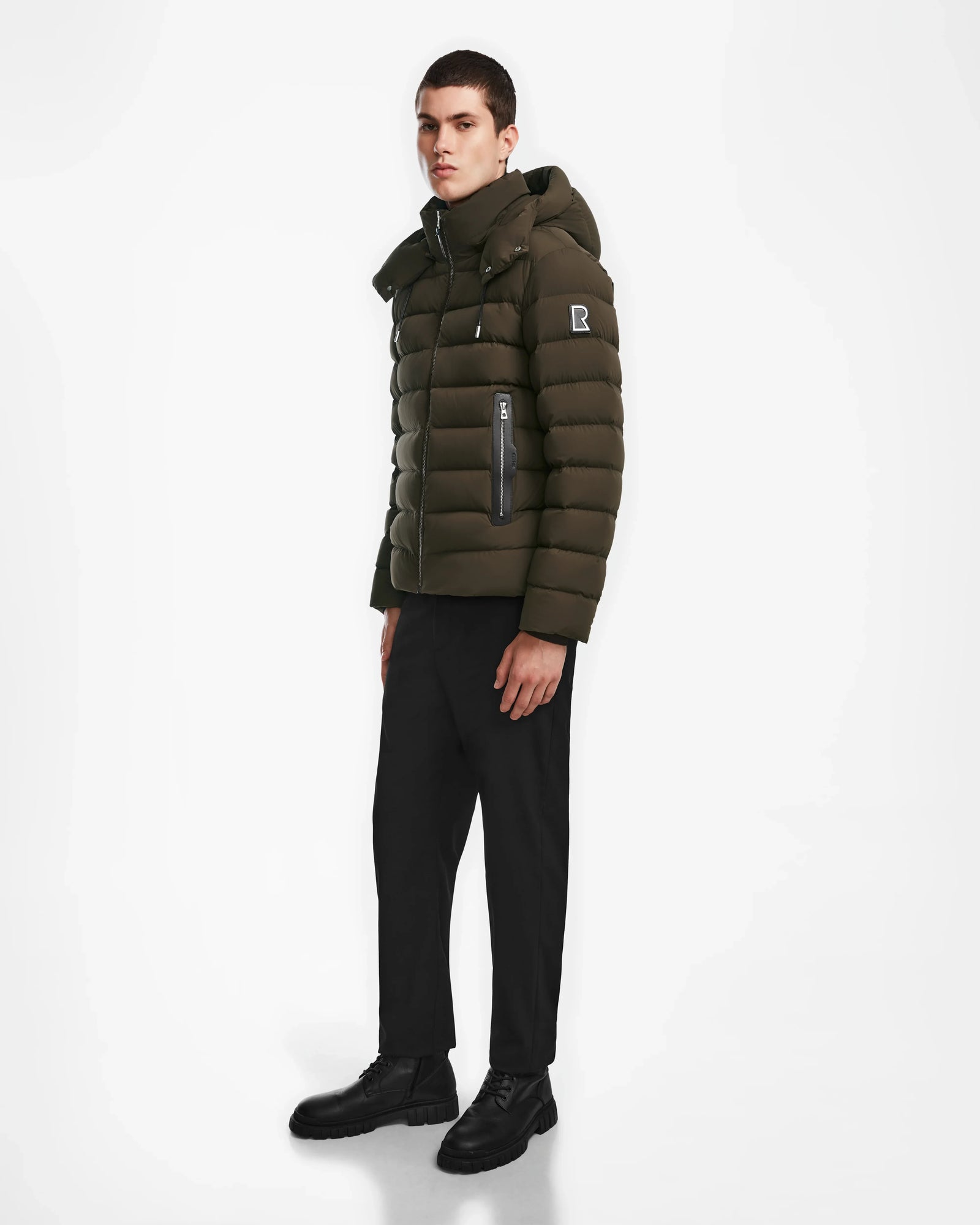 A man confidently showcases the NAVAN - 6124551 Army light down puffer by Rudsak, highlighting its warmth and modern design.