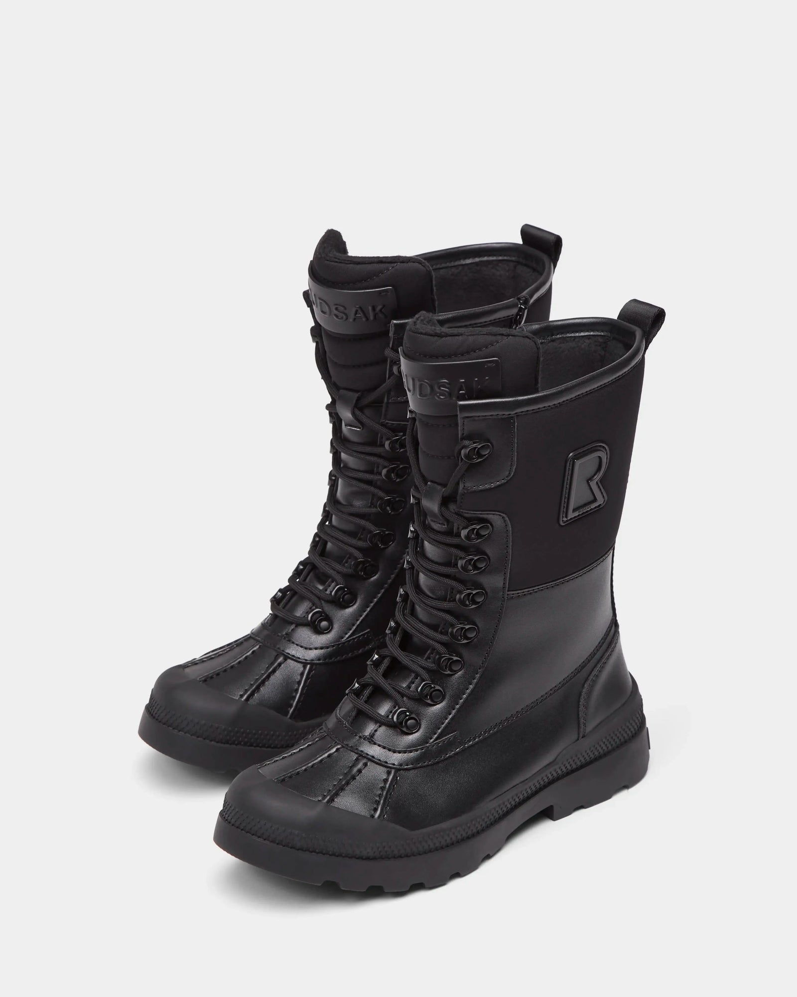 Rudsak's RITA - L222502 Black are women's black, mid-calf lace-up winter boots with thick soles, back pull tabs, a bold R logo, sturdy modern design, and weather-treated leather to keep your feet dry and stylish all season.