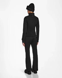 A person stands facing away against a plain white background, wearing the Rudsak ROSALIE - 8124784 Black ski jacket as part of an all-black winter outfit with matching beanie and pants.