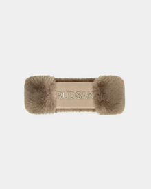 The Sandie - 8423507 Cement headband by Rudsak features fluffy beige faux fur on each end and an embroidered RUDSAK logo at the center, making it a chic winter accessory. Shown against a plain white background.