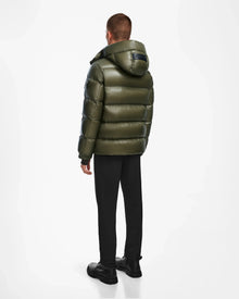 A man wearing the Rudsak VINCE S - 6124560 Loden Green mens down puffer jacket made from weather-resistant material.