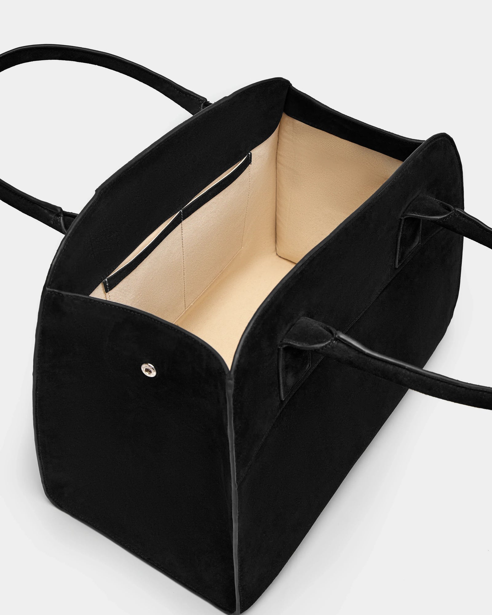 The Rudsak YASMINA L CS - 8324524 Black womens large suede tote bag features a sleek black exterior, beige lining, and inner pockets. Shown open and empty from a high angle against a light background.