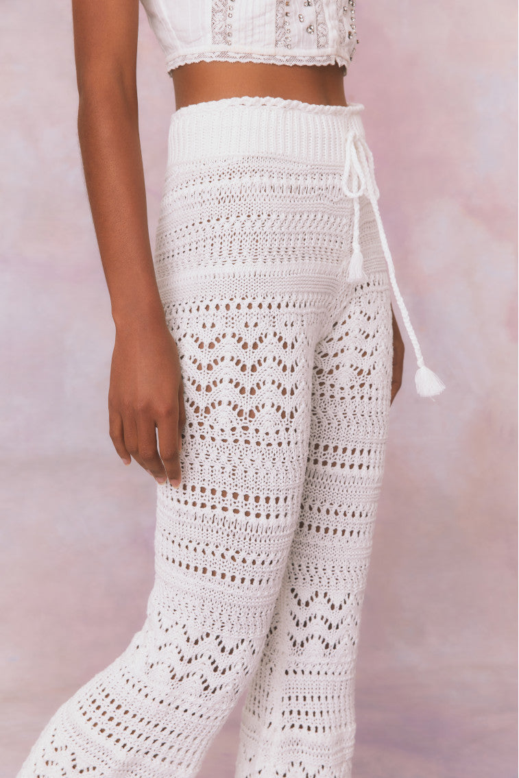 White cotton pointelle crochet floral flare pants with a self tie detail at center front on the double ribbed waistband.