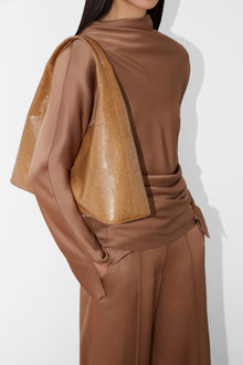 Brown satin top with draped fabric detail across the shoulder and textured gold accent panel.