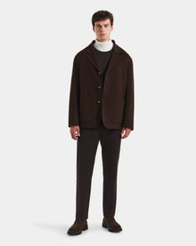A man faces forward in a sleek outerwear look: the Rudsak AIDEN - 6125558 Espresso jacket with large pockets and a removable shearling collar, styled over a white turtleneck, brown sweater, dark brown pants, and brown shoes against a white backdrop.
