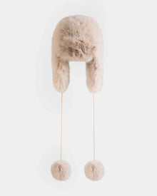 The RUDSAK DEMI - L425539 Vanilla is a beige faux-fur aviator hat with ear flaps and long strings ending in large fur pom-poms, shown against a plain white background.