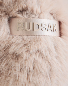 Close-up of soft, light beige faux fur on the DEMI - L425539 Vanilla women’s winter hat by Rudsak, featuring a shiny beige ribbon with “RUDSAK” in raised metallic letters on this luxe aviator style.