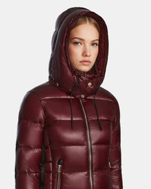 A young woman wears the Rudsak MIRRY S - L123545 winter coat in Wine with the hood up, looking ahead with a neutral expression against a plain light background.