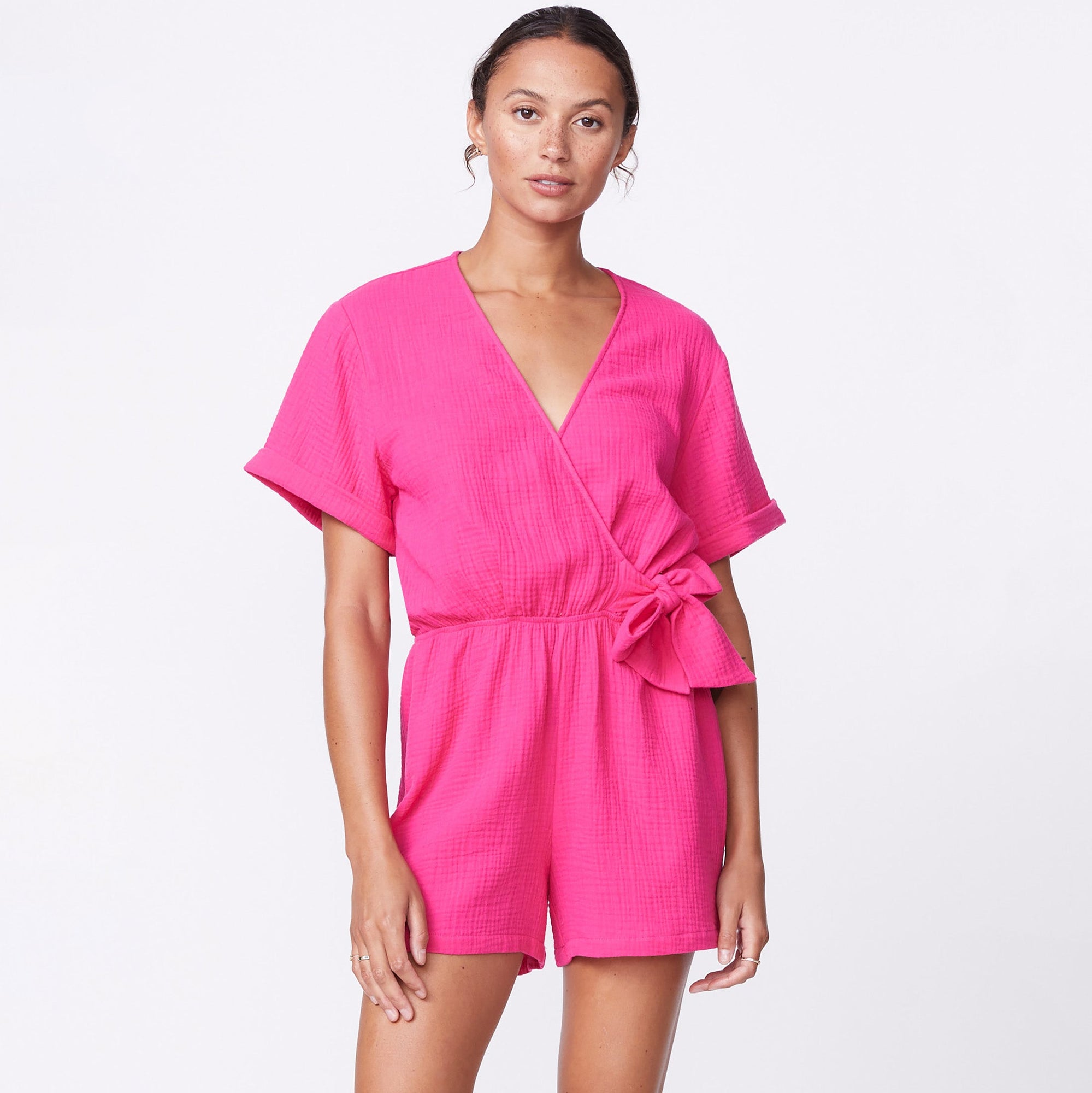 Front view of model wearing the gauze wrap romper in raspberry.