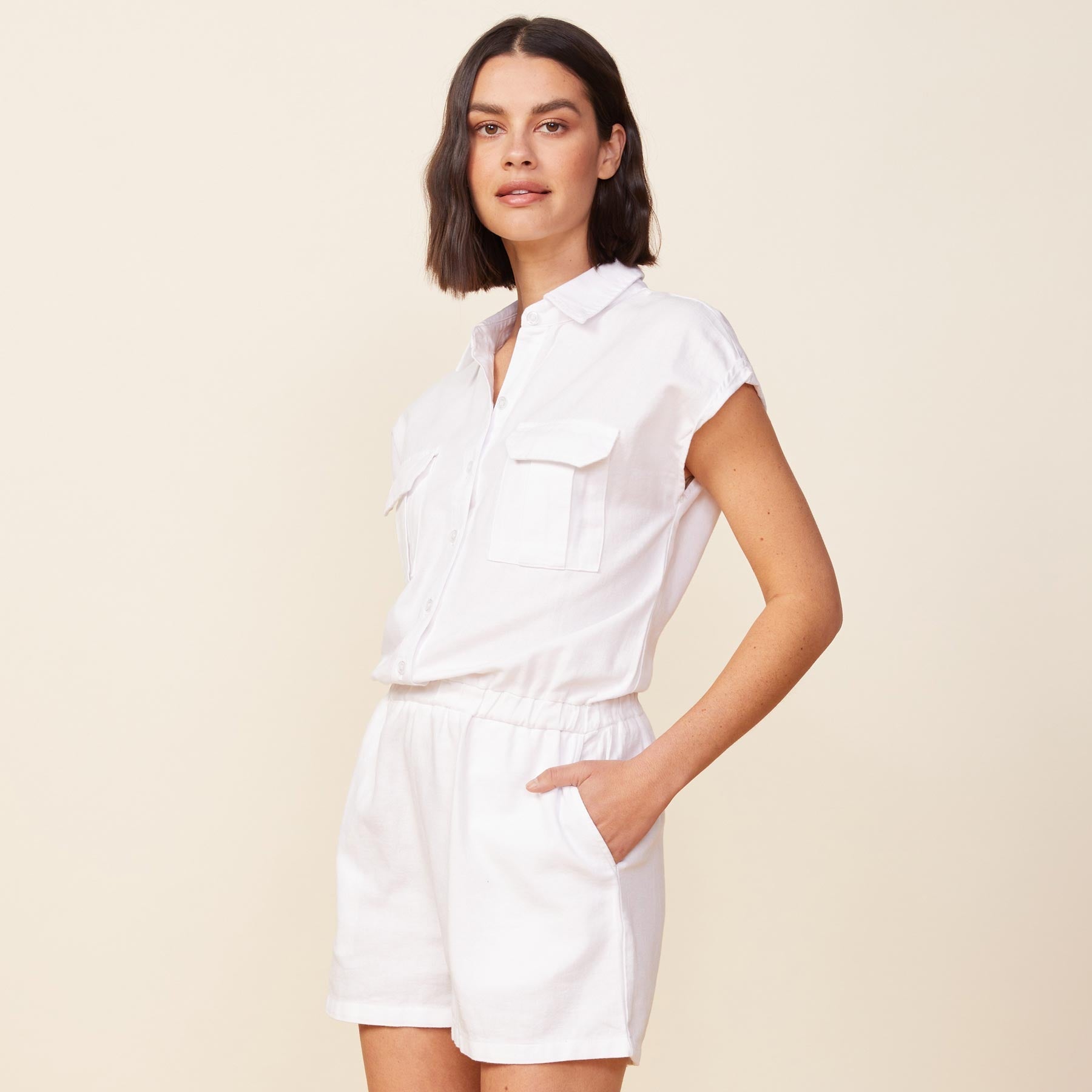 Side view of model wearing the cotton twill pocket romper in white.