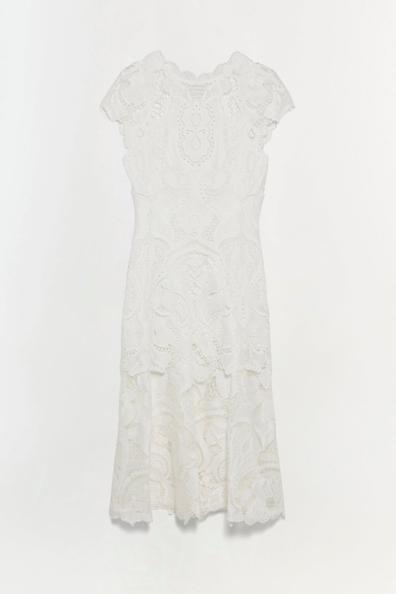 White lace dress with short sleeves, ornamental patterns throughout, and scalloped hemline.