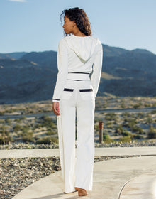 Woman in a white outfit standing on a pathway with mountains in the background