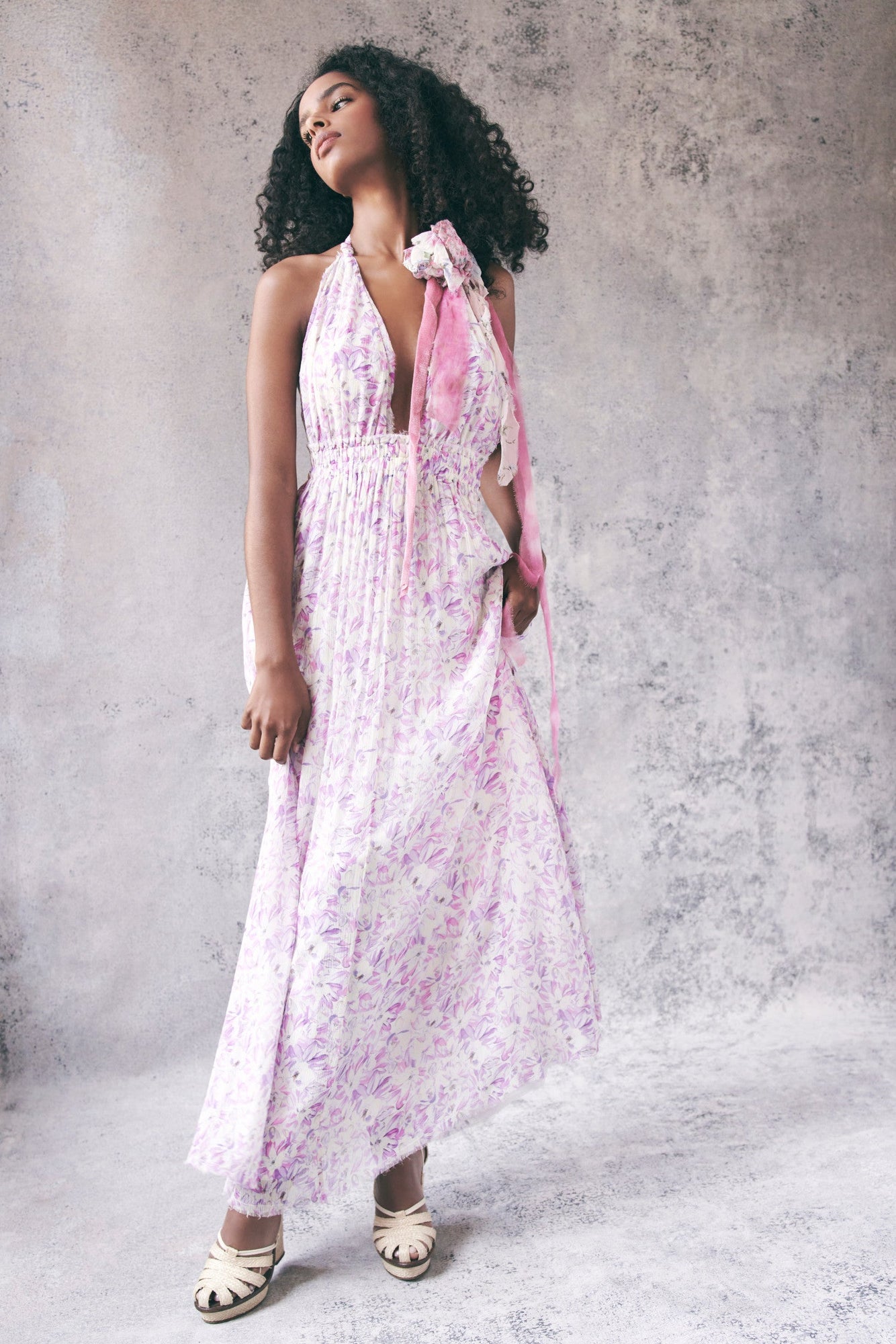 Model wearing white and purple floral halter maxi dress