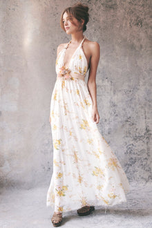 Model wearing white and yellow floral halter maxi dress